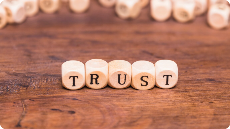 Wooden blocks spelling out the word 'TRUST' on a wooden surface, symbolizing the concept of trust and reliability.