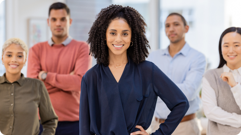A confident woman standing in front of a diverse group of people, symbolizing leadership and teamwork