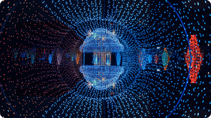 Vibrant and symmetrical display of colorful lights forming a tunnel-like structure with a spherical pattern in the center, creating a mesmerizing and futuristic visual effect
