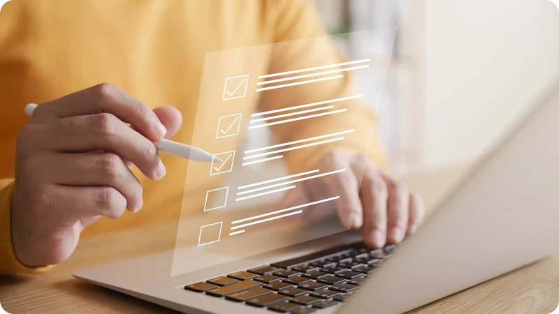 Person using a stylus to check items off a digital checklist displayed on a laptop screen.