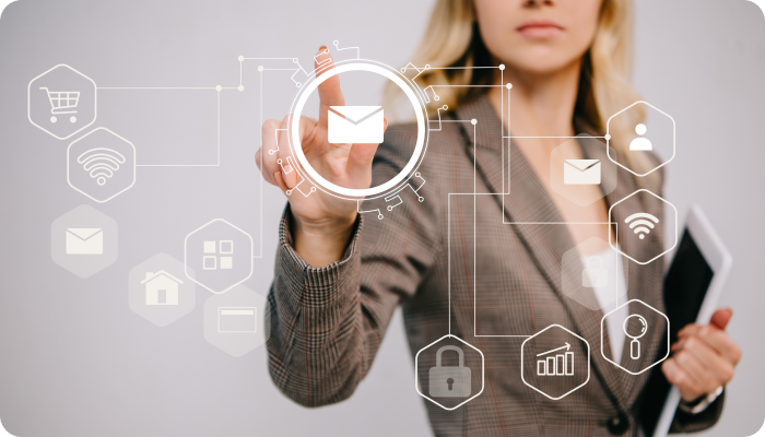 Businesswoman in a plaid suit using a virtual touchscreen interface with various icons related to email, shopping, Wi-Fi, and security, holding a tablet in her other hand.